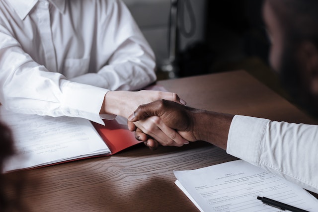 two people shaking hands after reviewing documents